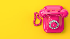 A pink vintage telephone on a yellow background